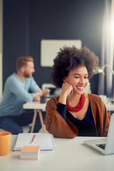 Mixed race businesswoman sitting in modern office and working on laptop