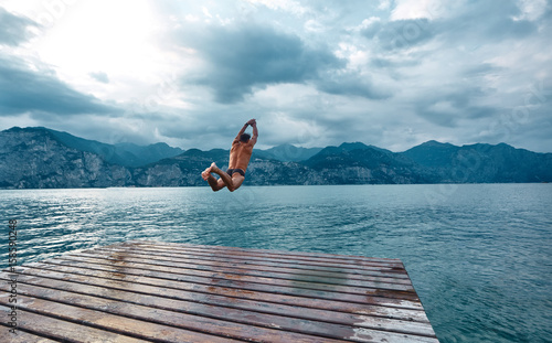 Obrazy skoki do wody  czlowiek-skaczacy-do-wody-z-molo-jezioro-lago-di-garda-wlochy