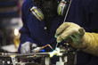 © Mint Images - Close up of skilled factory worker welding metal parts of a bicycle in a factory.