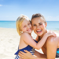 Poster - smiling healthy mother and daughter on seashore embracing