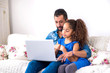 © Spectral-Design - Black father and his daughter siting on a couch with a laptop