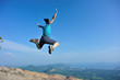 © lzf - successful woman jumping on rocky mountain peak
