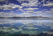 Reflections of blue skies and white puffy clouds in Walker Lake, Nevada. The water of the lake is still and reflects the sky above like a mirror.