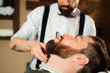 © nagaets - Master cuts hair and beard of men in the barbershop