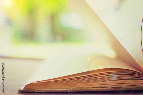 Fotografia, Obraz Open hardback book on wooden table with blurred backdrop