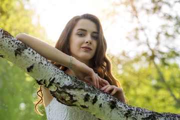 A girl with long hair at a birch branch in a park