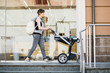 © Iryna - Full length side view of young sporty mother pushing baby stroller by beauty shop