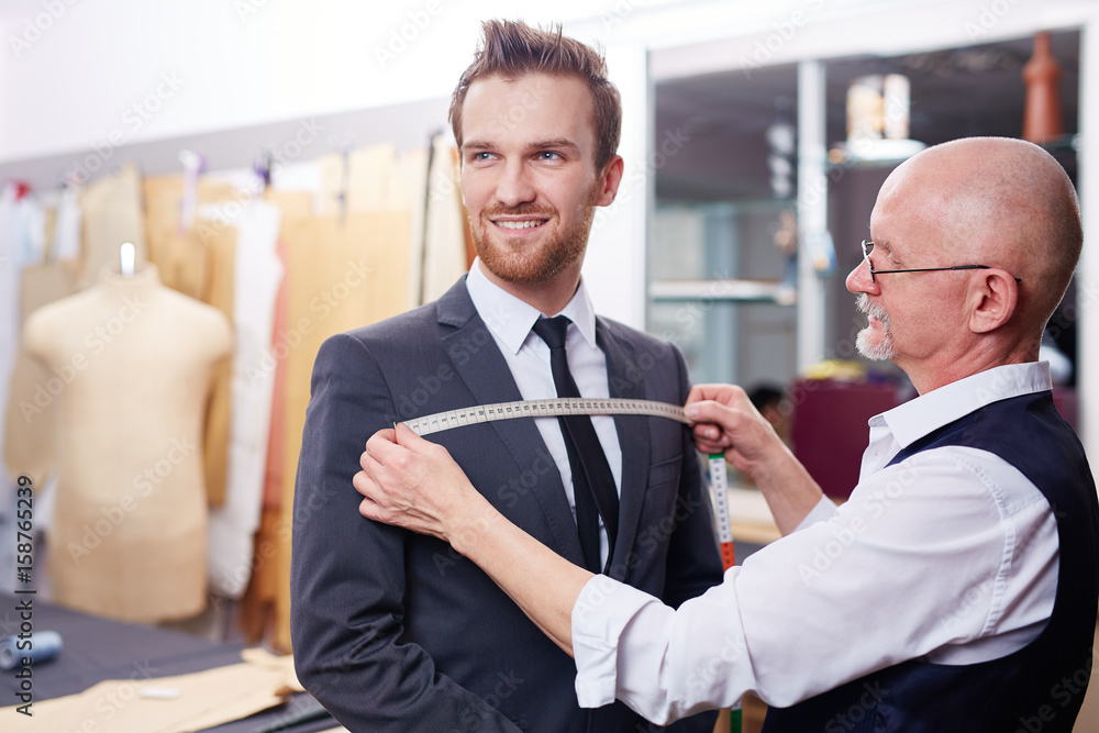 Portrait of handsome man smiling during model fitting of tailored suit ...