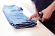 Side view closeup of man cutting jeans pants on tailors table in atelier