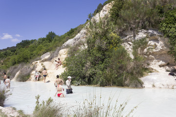 Bathing in the free area of Bagno Vignoni in Tuscany, Italy, free accessible hot springs puddle trough vegetation