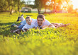 © guas - Sunny portrait happy father with son child lying on the green grass at summer evening on the sunset