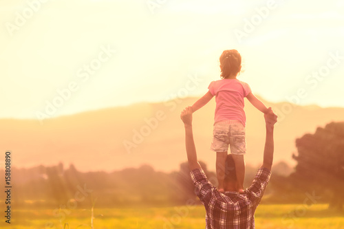 Fotografía Silhouettes of father and daughter playing together in the cornfield at sunset