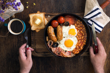 Poster - Man eats English breakfast on a dark wooden table