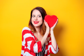 Woman with heart shape box on yellow background