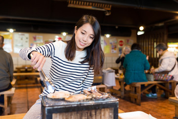 Canvas Print - Woman having grilled seafood in japanese restaurant