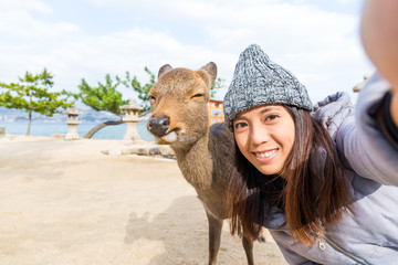 Wall Mural - Woman taking selfie with deer in Itsukushima