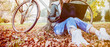 urban girl with laptop in park. woman in patched jeans with bicycle sitting on the grass. brownish autumn color tones. concept of freelancer communication technology eco-friendly lifestyle.