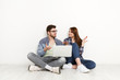 © Prostock-studio - Couple shopping online, sitting on floor at home