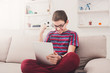 © Prostock-studio - Teenage boy using digital tablet on sofa at home