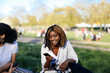 © Connect Images - Teenage girl, sitting on grass, looking at smartphone, smiling