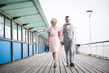 1950's Vintage Style Couple Strolling And Holding Hands On Pier