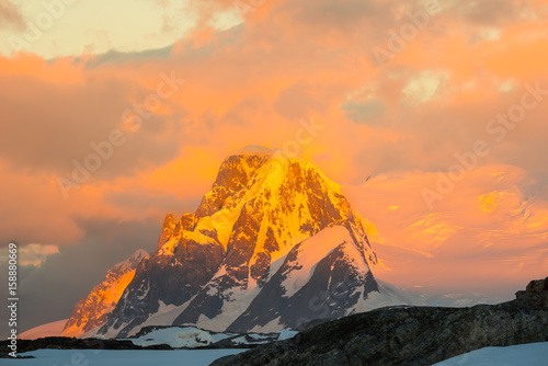 Glowing red mountains at sunset in Antarctica плакат