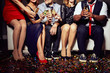 © pressmaster - Close-up shot of unrecognizable young friends sitting on sofa and clinking champagne flutes together