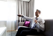 happy businessman with tv remote at hotel room