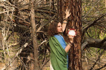 a young girl with an ethnic makeup and a tambourine in the forest. boho hippie style fashion portrait