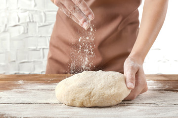 Wall Mural - Woman kneading  dough  on wooden table