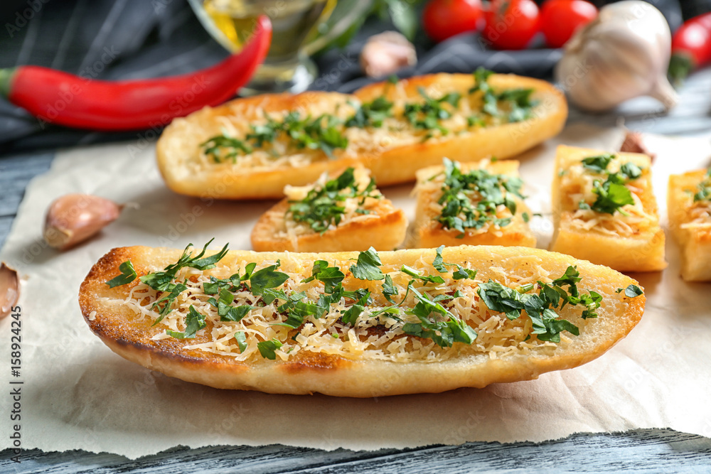 Tasty bread slices with grated cheese, garlic and herbs on parchment
