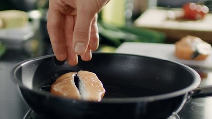 Wall Mural - Close-up of Hands Putting Red Fish Fillet on a Hot Pan. Shot on RED EPIC-W 8K Helium Cinema Camera.