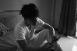 © Jestercine - Asian man using tablet with sad mood in the room, sadness portrait concept, black and white tone.