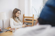 © Maskot - Woman using mobile phone sitting at table against wall in dorm