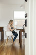 © Maskot - Full length side view of woman with daughter using laptop at home
