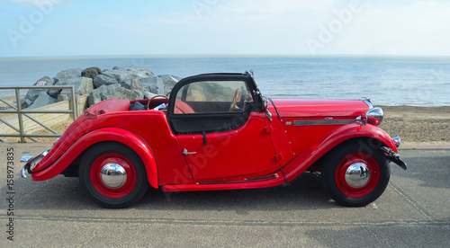 Cuadros en Lienzo Classic Red Singer Car parked on seafront promenade with sea in background