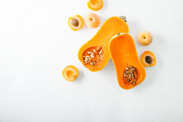 Wall Mural - Butternut squash halved with apricots on white background with copy space. Organic food concept.