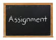 Assignment written in white chalk on a black chalkboard isolated on white