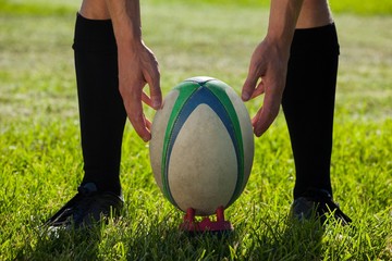 Wall Mural - Low section of rugby player getting ready to kick for goal