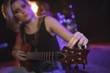 © wavebreak3 - Singer adjusting tuning peg of guitar in nightclub