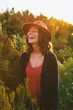 © BONNINSTUDIO/Stocksy - Woman laughing standing on the forest at sunset