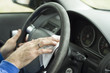 © Tomasz - Dłoń mężczyzny wyciera kierownice samochodu białą szmatką.