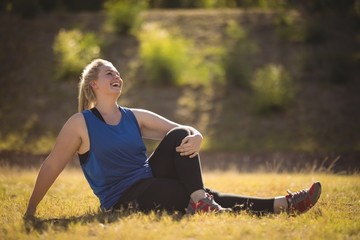 Wall Mural - Happy woman relaxing on grass during obstacle course