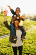 © BONNINSTUDIO/Stocksy - Mother giving her son a piggyback whilst playing with soap bubbles in the park