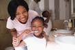 © WavebreakMediaMicro - Smiling mother with daughter brushing teeth in bathroom at home