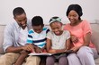© WavebreakMediaMicro - Family reading magazine while sitting on sofa at home