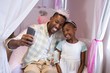© WavebreakMediaMicro - Father and daughter taking selfie while sitting on bed at home