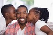 © WavebreakMediaMicro - Children kissing smiling father at home