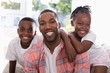 © WavebreakMediaMicro - Cheerful father and children sitting on couch at home