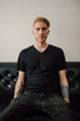 © Boris Jovanovic/Stocksy - Handsome young man sitting on the black sofa